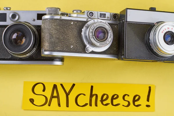 Tři Staré Retro Kamery Žlutém Pozadí Řekni Sýr Rukopis — Stock fotografie