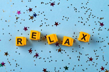 Düz sarı harf küpleri rahat bir şekilde yerleştirilmiş. Konfetileri mavi arkaplana yerleştirir.