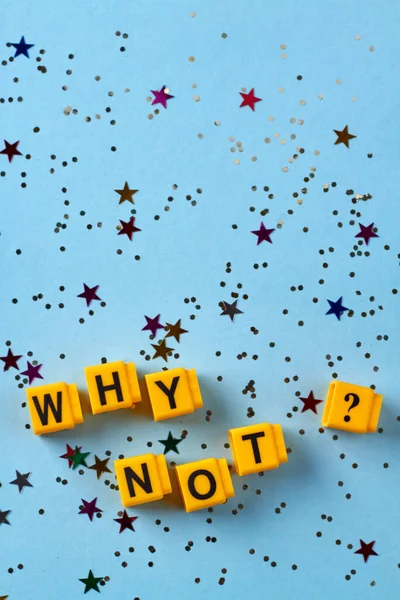 Sarı küplerin dikey görüntüsü, neden yazıtları sorgulamayalım? Mavi arka planda konfeti. Üst görünüm düzlüğü.