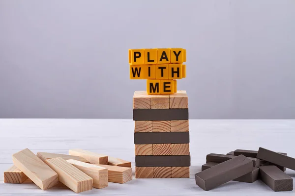 Stack of wooden blocks play with me letters. Tower building game jenga.