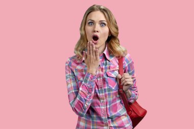 Happy surprised woman looking at camera standing on color background. Shocked young woman with open mouth standing on pink background.