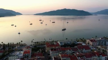 Marmaris marina at sunset. Aerial panoramic view from above. Top view of boats in the calm sea bay and mountains in the background. Go everywhere.