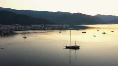 Scenic drone view of beautiful resort town at sunset. Sea bay with yachts surrounded by mountains. Marine landscape in the evening.