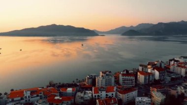 Aerial panoramic view of Marmaris town. City buildings, seascape and mountains. Beautiful urban and nature landscape at sunset.