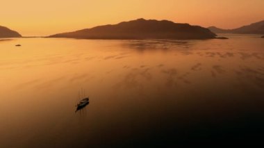 Beautiful morning sunrise over sea bay and mountains. Aerial drone view of boat on calm sea water at sunrise. Picturesque nature landscape. Go everywhere.
