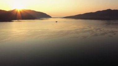 Dawn of the sun at sea. Sun rising over mountains. Panoramic view from drone. Nature landscape.