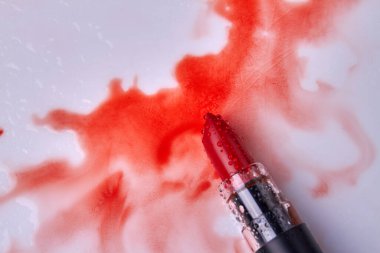 Top view red wet lipstick with wet stains. Makeup cosmetic accessory.