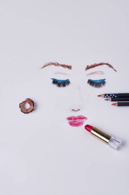 Womans face drawn by makeup pencils and lipstick. Vertical shot white background.