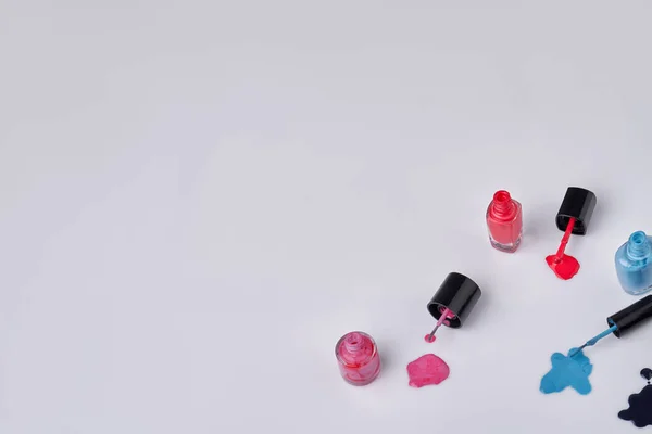 Colored nail polishes lacquers on a white background. Top view copy space.