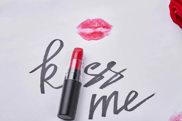 Red lipstick with kiss me writing and lips imprint. Close up top view.