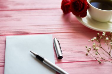 Close up ballpoint pen with blank paper. Pink wood background.
