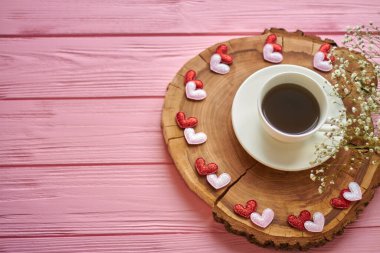 Top view coffee cup with hearts and flowers. Round rustic wooden board.