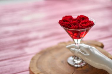 Mannequins hand with cocktail of red roses. Blurred background with copy space.
