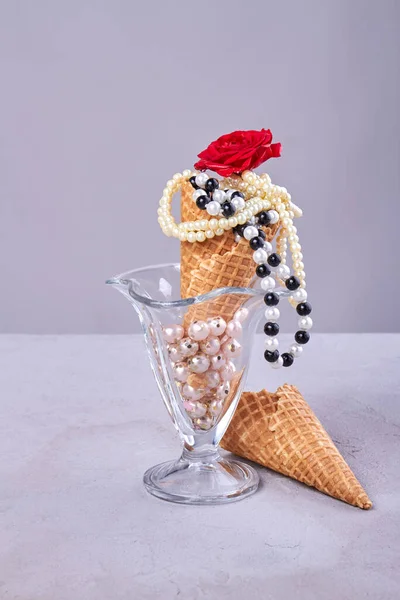 Glass ice cream cup with waffle cone and necklaces. Vertical shot white background.