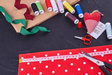 Top view sewing accessories with scissors and threads. Heart shaped needle pillow.
