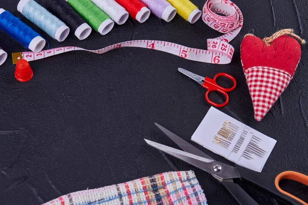 Top view sewing accessories with scissors and threads. Heart shaped needle pillow.