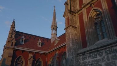 Red roof Roman Catholic Church of St Nicholas. Blue sky background.