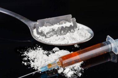 Close-up syringe and spoon with heroin. Drug addiction concept. White powder and shave razor for grinding.