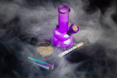 Purple glass bong with joint and a lot of thick white smoke. Top view marijuana weed addiction concept. clipart