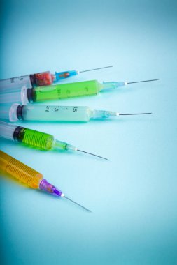 Set of syringes with colorful drugs or vaccines on blue background. Vertical shot blue background,.