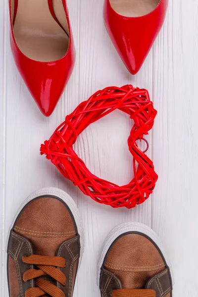 垂直ショットトップビューの靴と心 赤い女性の靴と茶色のメンズ履物上の白い机 — ストック写真