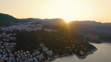 Sahil kasabasında gün batımının resmi. Şehir manzaralı deniz körfezi ve dağlar. İHA 'dan havadan panoramik görüntü.