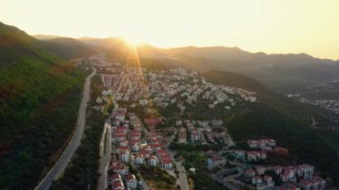 Gün batımında şehir manzarası ve dağlara karşı gökyüzü. İHA 'dan havadan panoramik görüntü.