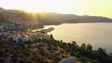 Gün batımında dağlara karşı manzaralı kasaba ve deniz koyları. İHA 'dan havadan panoramik görüntü.
