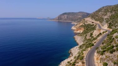 Turkuaz deniz ya da okyanus kıyısındaki dağ yolunun insansız hava aracının muhteşem manzarası. Gökten görkemli doğa manzarası.