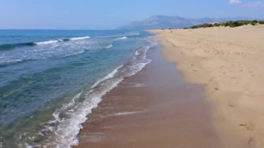 Kumsal ve mavi deniz dalgaları. Arka planda dağlar. Yaz tatili kavramı.
