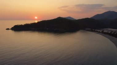 Akşamın deniz manzarası. Gün batımında gökyüzünün altında güzel dağlar ve deniz. İnsansız hava aracından panoramik görünüm.