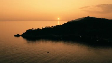 Denizin üzerinde güzel bir akşam güneşi. Gün batımında deniz ve dağların manzarası. Çarpıcı doğa manzarası.