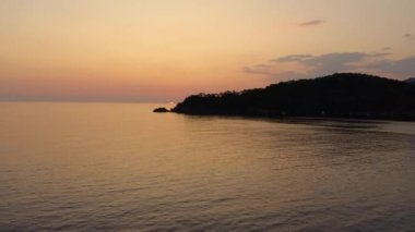 Akşamın deniz manzarası. Gün batımında gökyüzünün altında güzel dağlar ve deniz. İnsansız hava aracından panoramik görünüm.