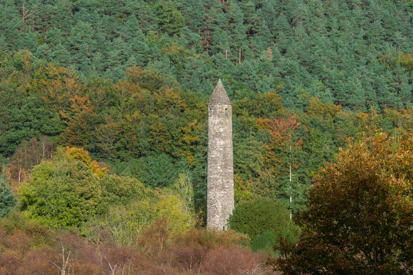 Glendalough Torre redonda con fondo de bosque de otoño. — Foto de Stock