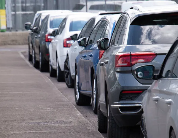 Lange Reihe von Autos geparkt in ruhiger Nachbarschaft auf sauberer, leerer Straße. Stockbild