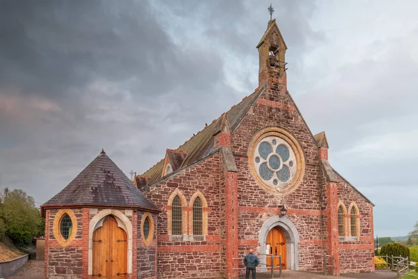 Iglesia desconocida construida de piedras rojas con el hombre de pie en la puerta y mirando hacia arriba. — Foto de Stock