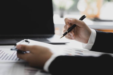 A business finance woman is reviewing a company's financial documents prepared by the Finance Department for a meeting with business partners. Concept of validating the accuracy of financial numbers.