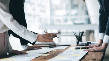 A desk in a company conference room has a group of business people attending and with supporting documents laid out, brainstorming sessions to fix and plan the company's growth. Business meeting idea.