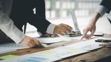 A desk in a company conference room has a group of business people attending and with supporting documents laid out, brainstorming sessions to fix and plan the company's growth. Business meeting idea.