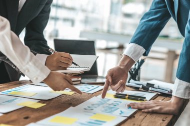 A desk in a company conference room has a group of business people attending and with supporting documents laid out, brainstorming sessions to fix and plan the company's growth. Business meeting idea.