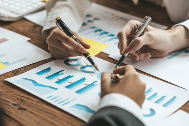 A desk in a company conference room has a group of business people attending and with supporting documents laid out, brainstorming sessions to fix and plan the company's growth. Business meeting idea.