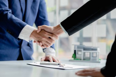 The salesperson of the housing estate in the project and the customer shake hands after successfully signing the contract. Concept of selling housing estates and real estate.