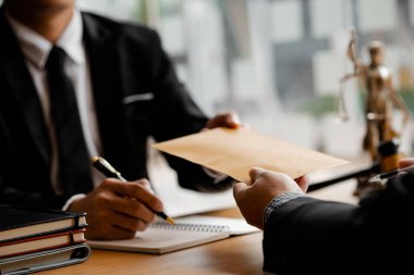 Avukatlar, iş ortaklarının zimmetine para geçirme durumlarına karşı ifade vermeye gelen müşterilerin belgelerini kabul ediyorlar. Yasal işlemler için avukat tutma kavramı.