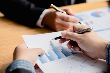 Two businessmen are reviewing the earnings summary and company financial documents that each department produces and submits for monthly audits. Concept of checking company information sheet.