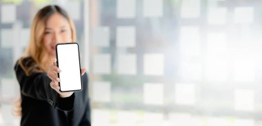 Asyalı kadın elinde beyaz, boş ekranlı bir telefon, reklam için akıllı telefon ekranı, akıllı telefon uygulaması. Reklamlar için kolaj fikirleri. Boşluğu kopyala.