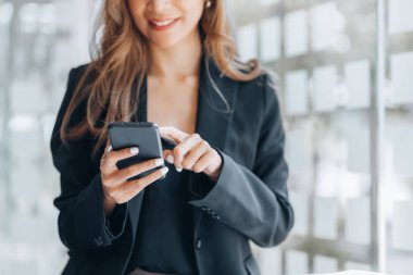 Young businesswoman looking at financial information from a mobile phone, she is checking company financial documents, she is a female executive of a startup company. Concept of financial management.