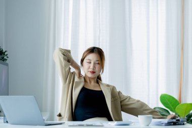 Çalışan bir kadın, ofiste bir iş kadını, uzun süre çalıştıktan sonra dinleniyor, yorgunluk ve strese neden oluyor, ofis sendromu var. Sıkı çalışma konsepti.