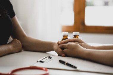 Doktor, muayene sonuçlarını bildirdikten ve hastalara tedavi yönergeleri ve reçete yazma konusunda bilgi verdikten sonra hastayı cesaretlendirmek için elini sıktı. Hastalık İnceleme Konsepti.