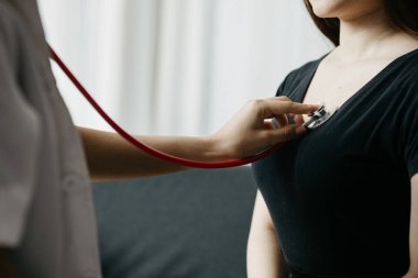 Stetoskop kullanan bir kadın doktor, hastayı muayene odasında muayene ediyor ve hastalara tedavi yönergeleri ve reçeteler hakkında bilgi veriyor. Hastalık İnceleme Konsepti.