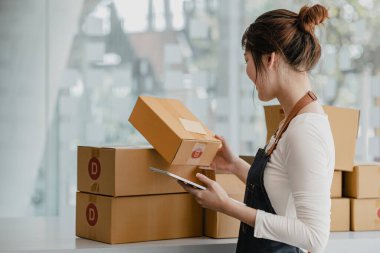 Güzel bir Asyalı işletme sahibi online bir dükkan açıyor, müşterilerin siparişlerini kontrol ediyor, bir kurye şirketi aracılığıyla mal gönderiyor, bir kadının online iş kurma kavramı.